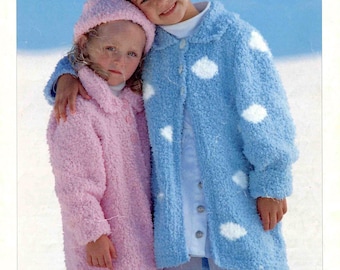 May include: Two children wearing matching knitted coats and hats. One coat is light blue with white cloud-shaped accents, the other is pink. The image has the word "SNOWFLAKE" at the top and "SIRDAR" at the bottom.