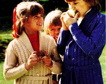 May include: Vintage Patons knitting pattern cover featuring three children wearing knitted cardigans. The cardigans are beige and blue, with a cable knit design and a belt. The text "Double Knitting" and "22-28 in." are visible.