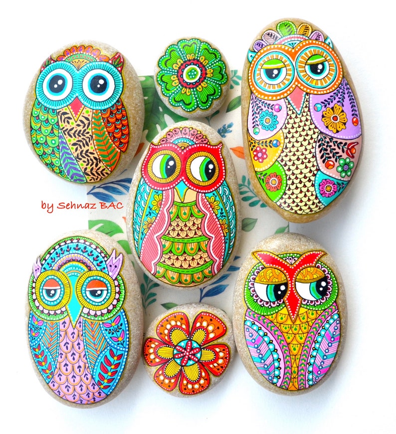 Puede incluir: Seis piedras pintadas con dise&ntilde;os coloridos de b&uacute;hos. Los b&uacute;hos tienen ojos grandes y est&aacute;n decorados con intrincados patrones. Las piedras son de diferentes formas y tama&ntilde;os.