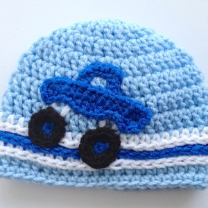 May include: Blue and white crocheted baby hat with a blue car applique and black wheels.