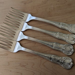 Könnte beinhalten: Set aus vier silbernen Gabeln mit verzierten Griffen. Die Gabeln haben ein traditionelles Design mit einem dekorativen Muster auf dem Griff.