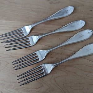 Pode incluir: Quatro garfos de prata com cabos ornamentados. Cada cabo é gravado com a palavra "Cher".
