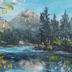 Puede incluir: Una pintura que representa una escena de lago de montaña con una montaña en el fondo, un río en primer plano y árboles en las orillas del río. El cielo es azul y el agua es azul claro.