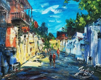 May include: A colorful oil painting depicting a street scene with buildings on both sides of the street. The buildings are painted in shades of yellow, white, and blue. There are figures walking down the street, and the sky is a bright blue with white clouds.