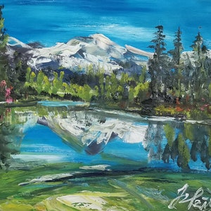 Puede incluir: Una pintura de una escena de lago de montaña con una montaña cubierta de nieve reflejada en el agua. El lago está rodeado de árboles verdes y un cielo azul.