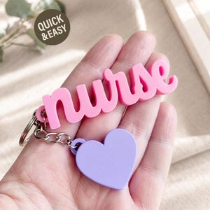 May include: A keychain featuring a pink, three-dimensional script word that reads nurse, attached to a silver metal ring and a light purple heart-shaped charm. The text QUICK & EASY is printed in a dark circle in the upper left corner.