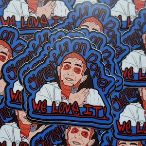May include: A sticker featuring a cartoon man with red hair and a red face, wearing a white lab coat and a blue shirt. The sticker has a blue background with the text "Shangri La on dope! We Love It!" in red and white.
