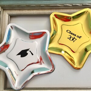 May include: Two gold and silver star-shaped paper plates. The gold plate has the text "Class of 2017" printed on it. The silver plate has a graduation cap graphic.