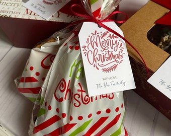 May include: Christmas-themed gift bags and boxes. The bags are clear with red and green stripes and white polka dots. Each bag is tied with a red ribbon and a tag that reads "Merry Christmas" and "With Love, The Yu Family."
