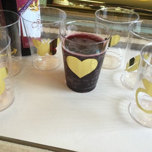 Puede incluir: Seis vasos de pl&aacute;stico transparentes con dise&ntilde;os de l&aacute;mina dorada. Los dise&ntilde;os incluyen un coraz&oacute;n, un p&aacute;jaro, una pluma, un anillo y una abeja. Un vaso contiene un l&iacute;quido rojo oscuro.