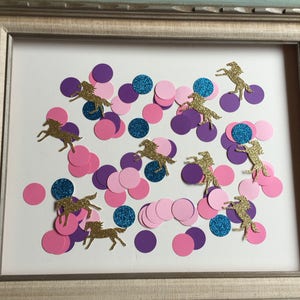 May include: A framed image of confetti with pink, purple, and blue circles and gold glitter unicorn silhouettes.