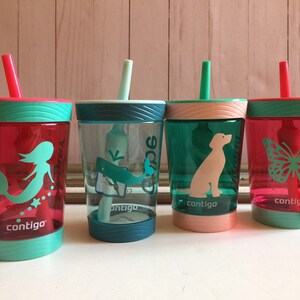 May include: Four colorful plastic cups with straws and different designs. The cups are turquoise, pink, green, and red. The designs include a mermaid, a whale, a dog, and a butterfly. The cups are all labeled "contigo".