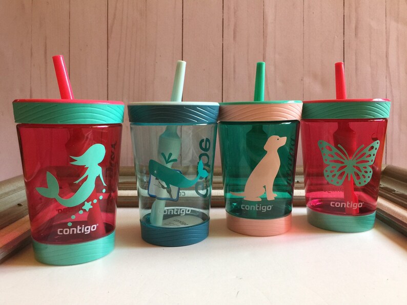 May include: Four colorful plastic cups with straws and different designs. The cups are turquoise, pink, green, and red. The designs include a mermaid, a whale, a dog, and a butterfly. The cups are all labeled "contigo".