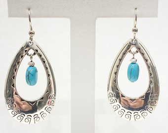 May include: Silver teardrop shaped earrings with a turquoise stone hanging from the bottom. The earrings have a decorative design around the edge.