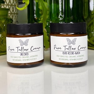 May include: Two amber glass jars with black lids containing a white cream. The jars have labels with the text "Pure Tallow Cream" and a butterfly logo. One jar is labeled "Unscented" and the other is labeled "Revive-Restore-Awaken". Both jars have the text "100% Grass Fed, Organic, Hydrating, Nourishing, Vitamins A, D, E & K."