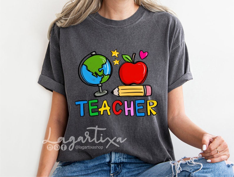 K&ouml;nnte beinhalten: Ein dunkelgraues T-Shirt mit einem bunten Grafikdesign, das einen Globus, einen Apfel, einen Bleistift und das Wort "TEACHER" zeigt.