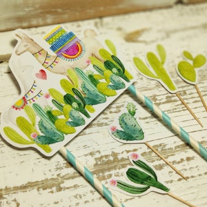 May include: A set of five cake toppers featuring a llama with a colourful saddle and cacti. The llama and cacti are printed on white cardstock and attached to wooden skewers. The skewers are decorated with blue and white striped paper.