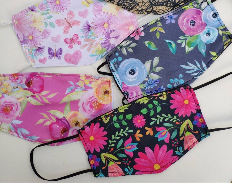May include: Four different fabric face masks with floral patterns. The masks are all in different colors and have different floral designs. The masks are all made of a soft, breathable fabric.