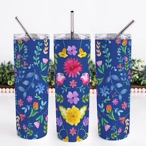 Könnte beinhalten: Drei Edelstahlbecher mit Deckel und Strohhalmen. Jeder Becher zeigt ein anderes Blumenmuster auf blauem Hintergrund. Die Blumen sind in den Farben Rosa, Gelb, Lila und Orange.