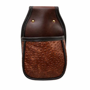 May include: A brown leather utility pouch featuring a smooth upper section with two gold-tone metal rivets and a textured, ostrich-patterned lower pocket. The entire pouch is edged with dark brown piping, creating a structured, durable design.