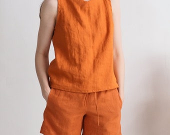 Puede incluir: Un conjunto de top sin mangas y pantalones cortos a juego en un vibrante color naranja quemado. El top presenta un escote ancho y un corte relajado, mientras que los pantalones cortos tienen una cintura elástica con cordón ajustable.