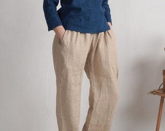 May include: A long-sleeved dark blue top with a round neckline paired with loose-fitting beige trousers. The trousers feature an elasticated waistband and side pockets. The outfit is presented as a set of two separate clothing items.