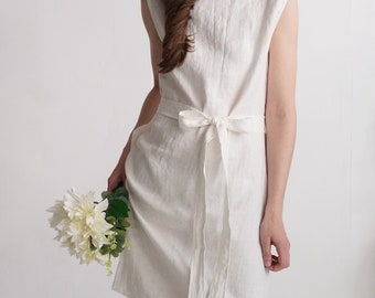 May include: A sleeveless off-white dress made of a textured fabric, featuring a round neckline and a matching tie-waist belt. The dress has a straight silhouette that falls to the knee, with a clean, simple design and a visible fabric weave.