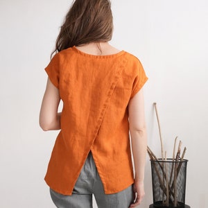 Könnte beinhalten: Ein orangefarbenes Leinenoberteil mit kurzen Ärmeln und einem geteilten Rücken.