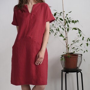 Peut inclure: Une robe en lin rouge avec un col en V et des manches courtes. La robe a une coupe ample et une forme l&eacute;g&egrave;rement trap&egrave;ze.