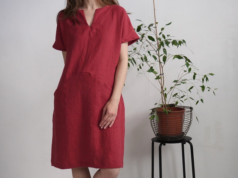 Peut inclure: Une robe en lin rouge avec un col en V et des manches courtes. La robe a une coupe ample et une forme l&eacute;g&egrave;rement trap&egrave;ze.