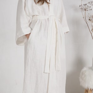 May include: A white linen robe with a long, flowing silhouette and a tie belt. The robe has a relaxed, comfortable fit and is perfect for lounging around the house.