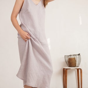 Puede incluir: Un vestido midi sin mangas de color lavanda claro con escote en V y una silueta relajada y fluida. La prenda est&aacute; confeccionada con un tejido texturizado y cae de forma holgada, mostrando un dise&ntilde;o sencillo con tirantes finos y un dobladillo recto.