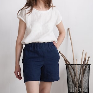 May include: A white short-sleeved top with a round neckline paired with navy blue shorts featuring an elasticized waistband and side pockets. The shorts are constructed from a solid-colored fabric and sit at the natural waistline.