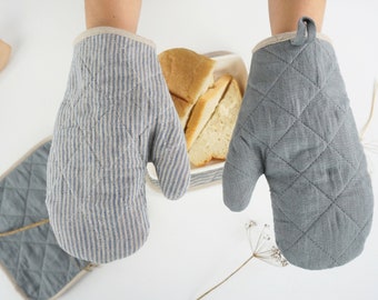 May include: Two oven mitts, one with blue and white stripes and one solid gray, both with quilted designs. The mitts are made of a linen fabric.