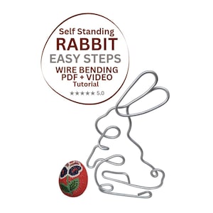 Puede incluir: Una escultura de conejo de alambre y un huevo de Pascua. El conejo es de alambre plateado y está junto a un huevo rojo con bordados florales. La imagen incluye el texto "Self Standing Rabbit Easy Steps Wire Bending PDF + Video Tutorial".