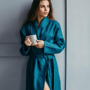 Woman wearing teal linen bathrobe holding mug – handmade robe from soft European flax linen