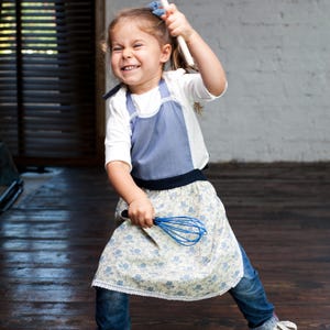 Girl in denim-blue apron mixing dough, children’s personalized art apron.