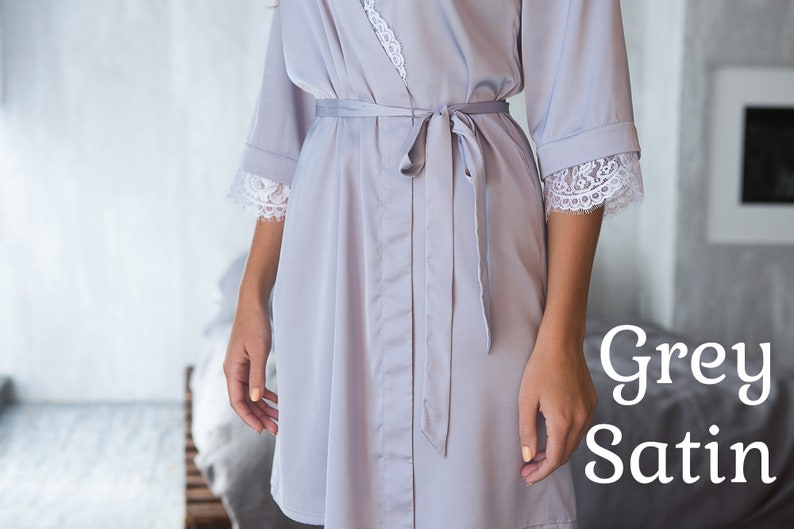 May include: A grey satin robe with white lace trim on the sleeves and a matching tie belt.