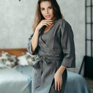 Woman in grey linen kimono-style robe seated indoors – soft natural loungewear