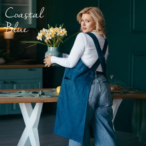 A curvy model in a relaxed-fit natural linen apron, emphasizing its comfortable cross-back design.