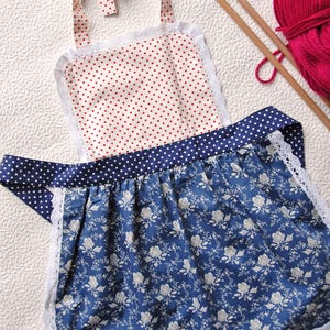 Details of cute handmade kitchen apron for girls in red polka dot and blue floral retro cotton.