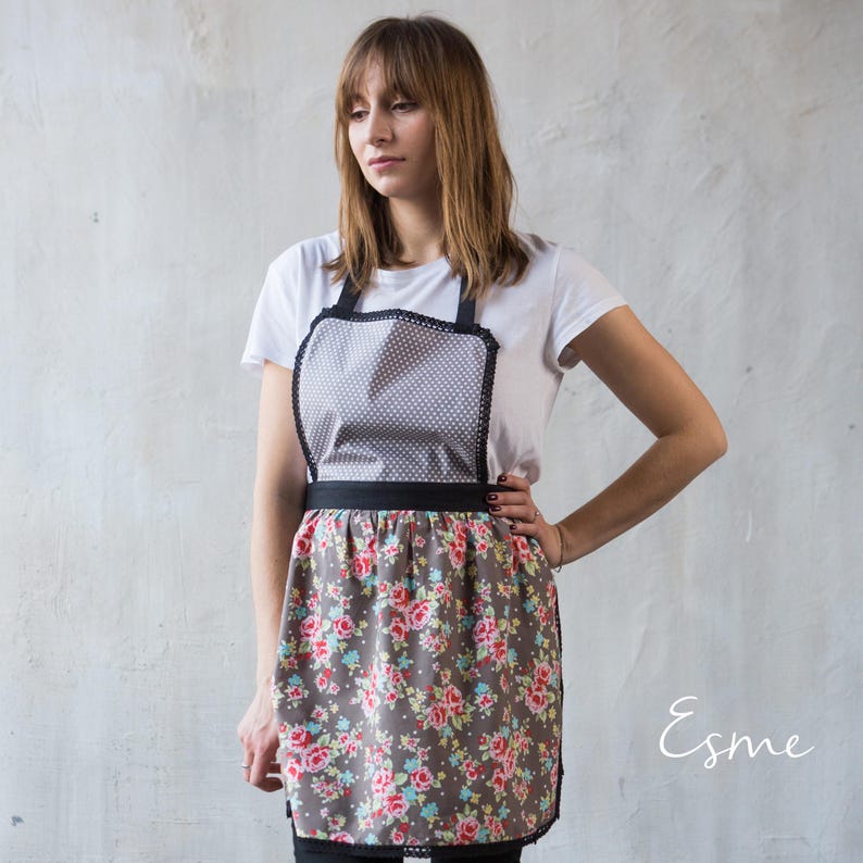 Woman modeling a cute greya nd black floral apron with retro waist tie.