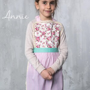 Girl wearing pink apron with floral top, perfect for baking or pretend play