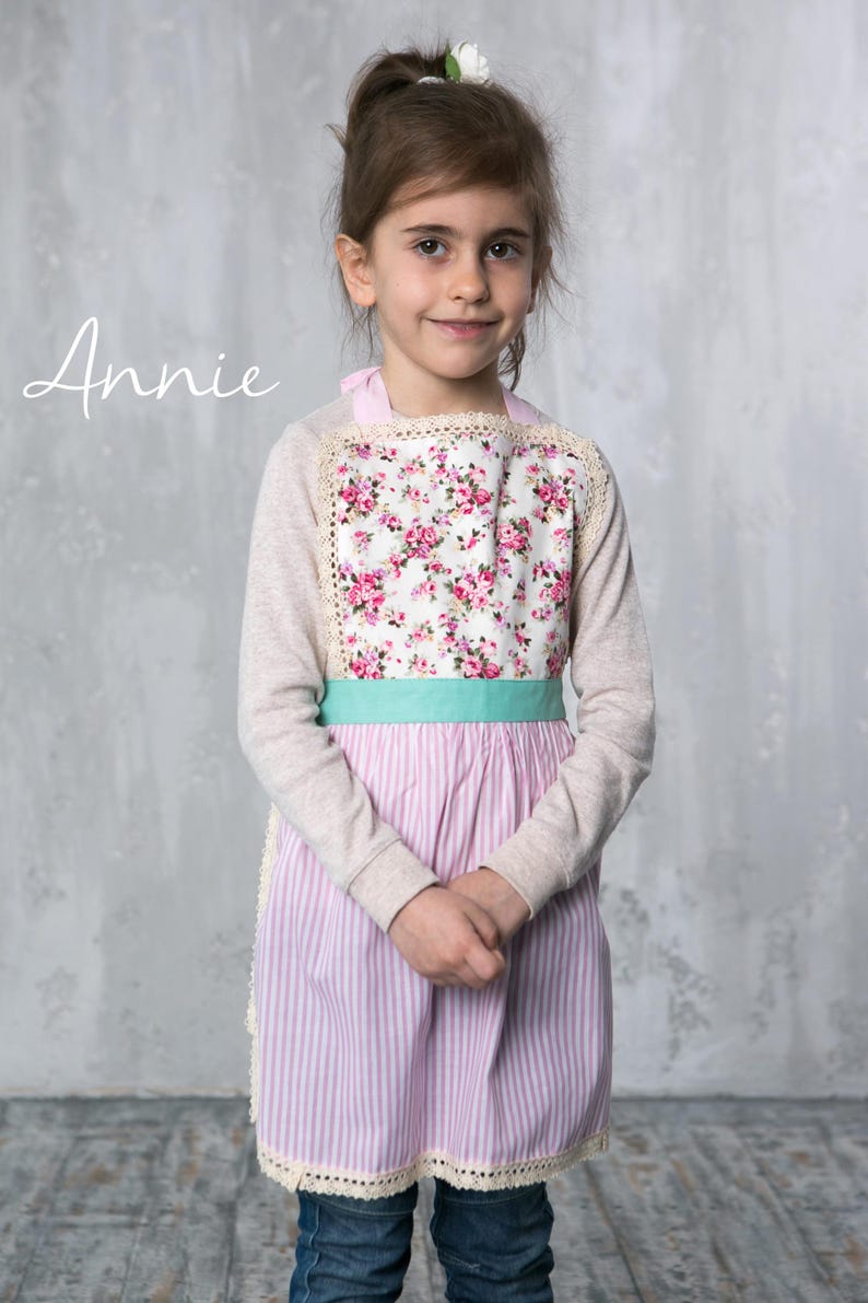 Girl wearing pink apron with floral top, perfect for baking or pretend play