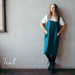 A crafter showcasing a teal linen apron, posing confidently in a sleek studio space.