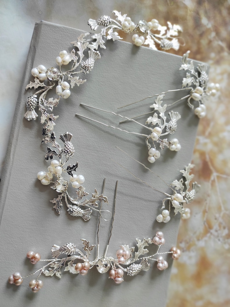 May include: A set of six silver hair combs with pearl and pink pearl accents. Each comb features a thistle design with leaves and a pearl cluster.