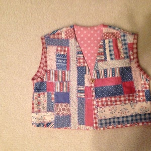 May include: A patchwork vest with a variety of colors and patterns, including red, blue, and white. The vest has a V-neck and is sleeveless.