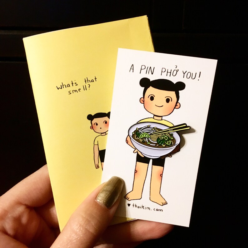 May include: A yellow card with the text "what's that smell?" and a cartoon illustration of a person. A second card reads "A PIN PHO YOU!" and features a cartoon person holding a bowl of pho.