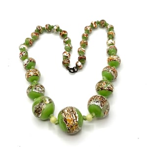 May include: A vintage necklace with large, round, lime green beads, speckled with gold and silver. The beads are strung with smaller green beads and a dark metal clasp. A unique piece of jewellery.