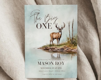 May include: A rectangular invitation card featuring a watercolor illustration of a deer standing on a rocky shoreline by a lake. The text reads: JOIN US FOR The Big ONE celebrating the 1st birthday of MASON ROY NOVEMBER 29 AT 2PM 8879 Lewis Road Alden, Ohio regrets only to 555-9945.
